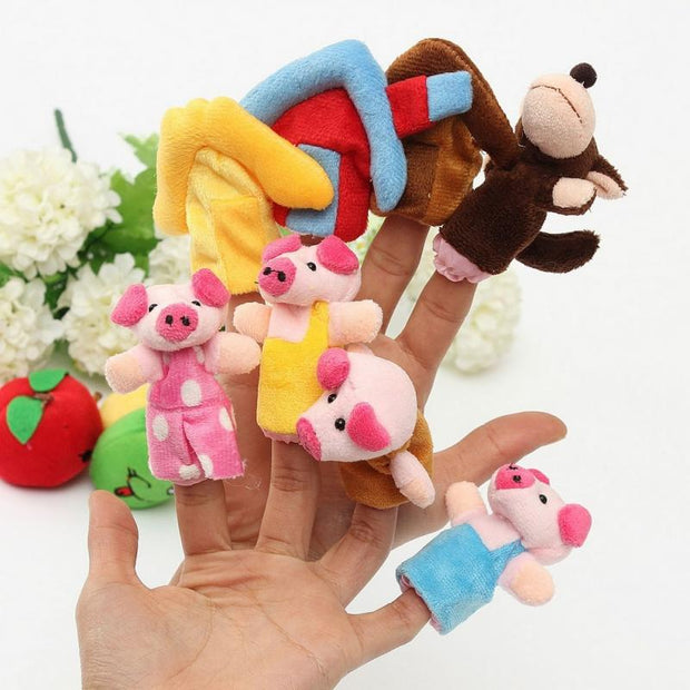 Two hands over each other with one hand the 3 little pigs and mommy pig, and the hand in the back has the yellow straw, brown wood, and red brick houses with the BIG BAD WOLF finger puppets.